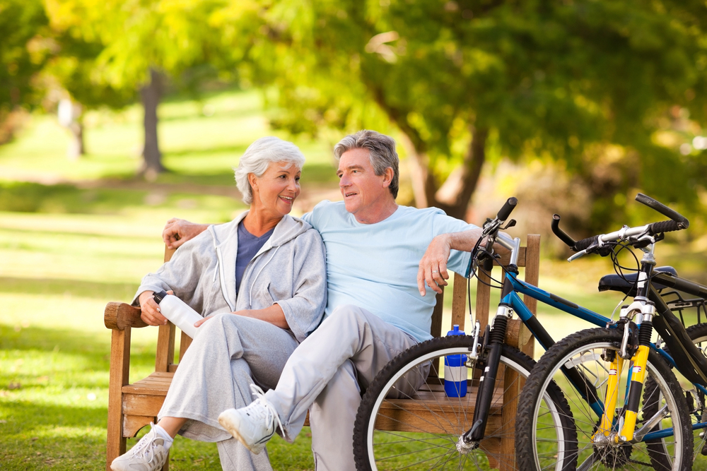 Happily retired couple sitting on bench after bike ride